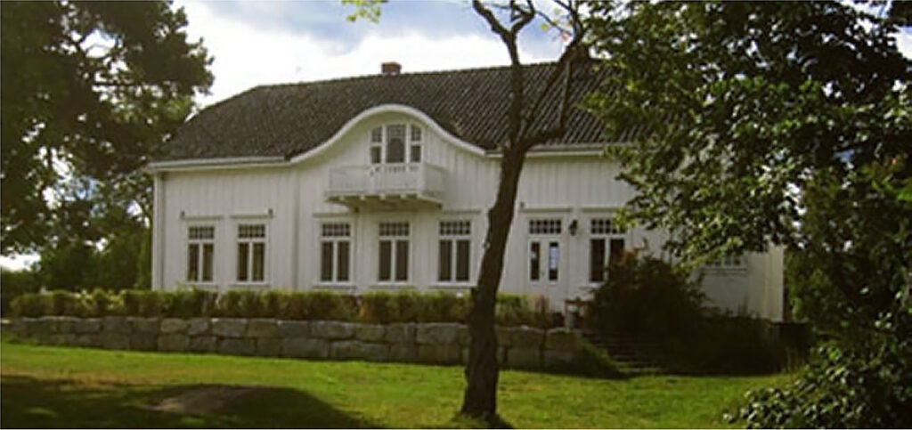 Hovedbygningen på Hellviktangen på Nesodden, en hvitmalt trevilla med hage og trær i forgrunnen.